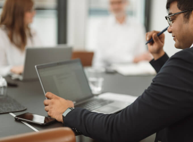 Mitarbeiter in einer Business-Besprechung mit Laptop, konzentriert auf digitale Unternehmens- oder Finanzprozesse.
