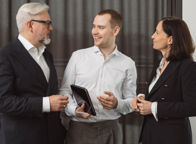 Drei Personen in einer Business-Besprechung mit Tablet, konzentriert auf Strategie, Abstimmung und digitale Unternehmensprozesse.