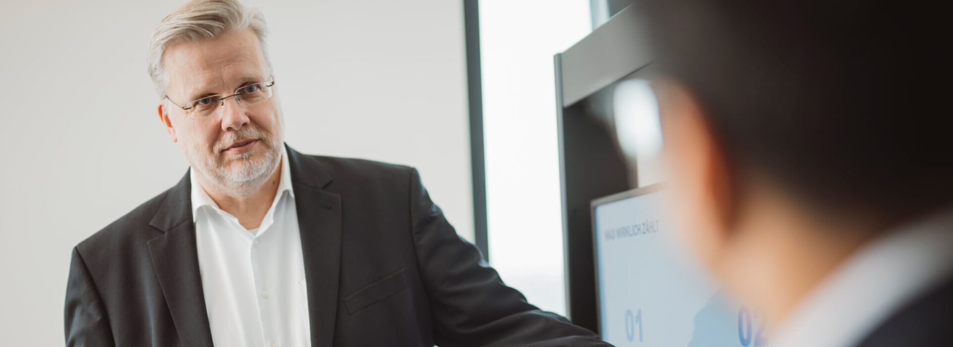Mitarbeiter präsentiert in einer Business-Besprechung strukturierte Finanz- oder Abrechnungsprozesse an einem Bildschirm.