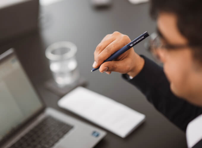 Mitarbeiter in einer Business-Besprechung mit Laptop und Stift, konzentriert auf strategische Abstimmung und strukturierte Unternehmensprozesse.