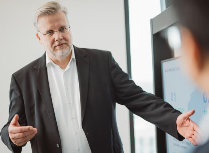 Mitarbeiter pr&auml;sentiert in einer Business-Besprechung strukturierte Finanz- oder Abrechnungsprozesse an einem Bildschirm.