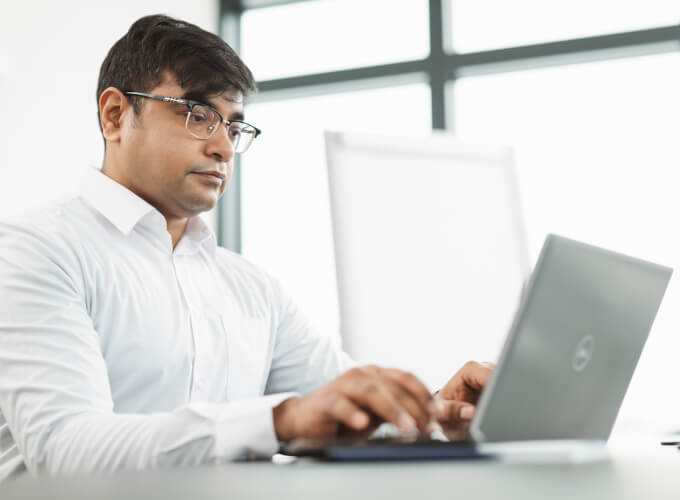 Drei Personen in einer Business-Besprechung arbeiten gemeinsam an einem Laptop und stimmen strukturierte Unternehmensprozesse ab.