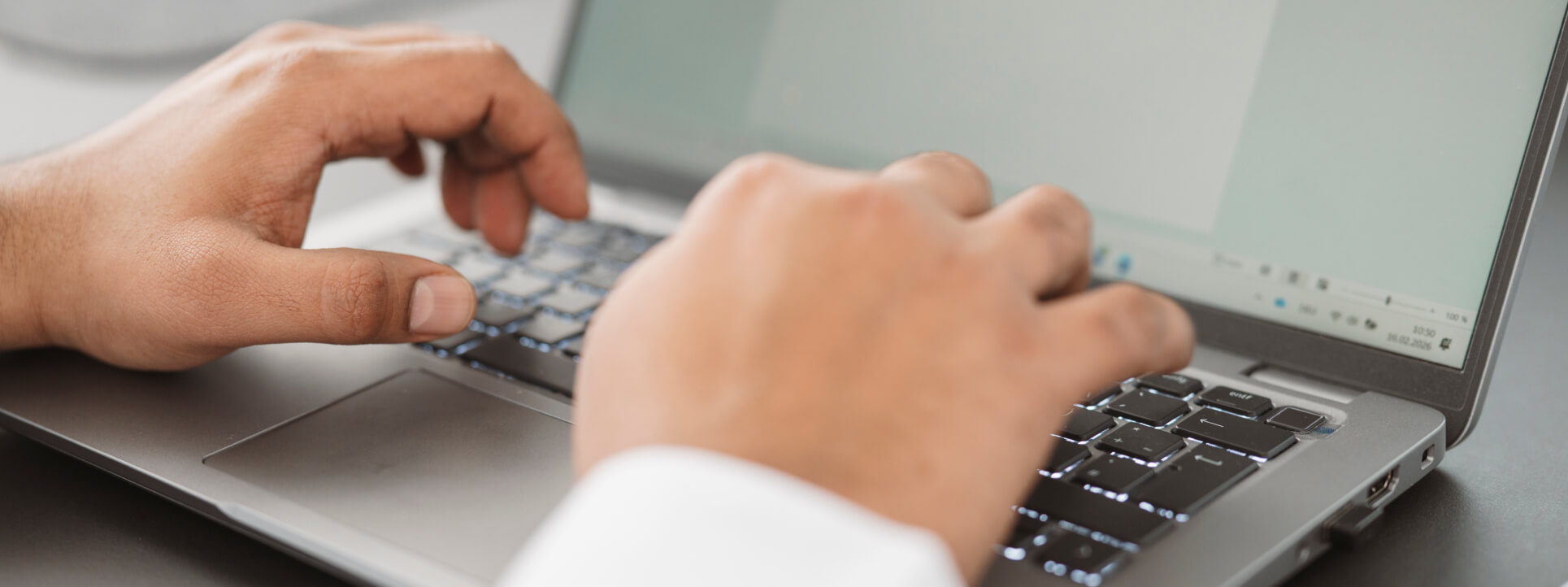 Hands of a person typing on a laptop, focused on digital processes and software.