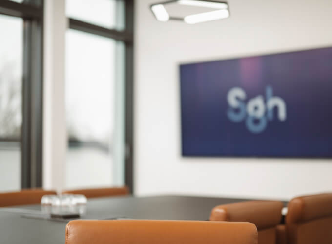 Besprechungsraum mit Konferenztisch und SGH-Logo im Hintergrund