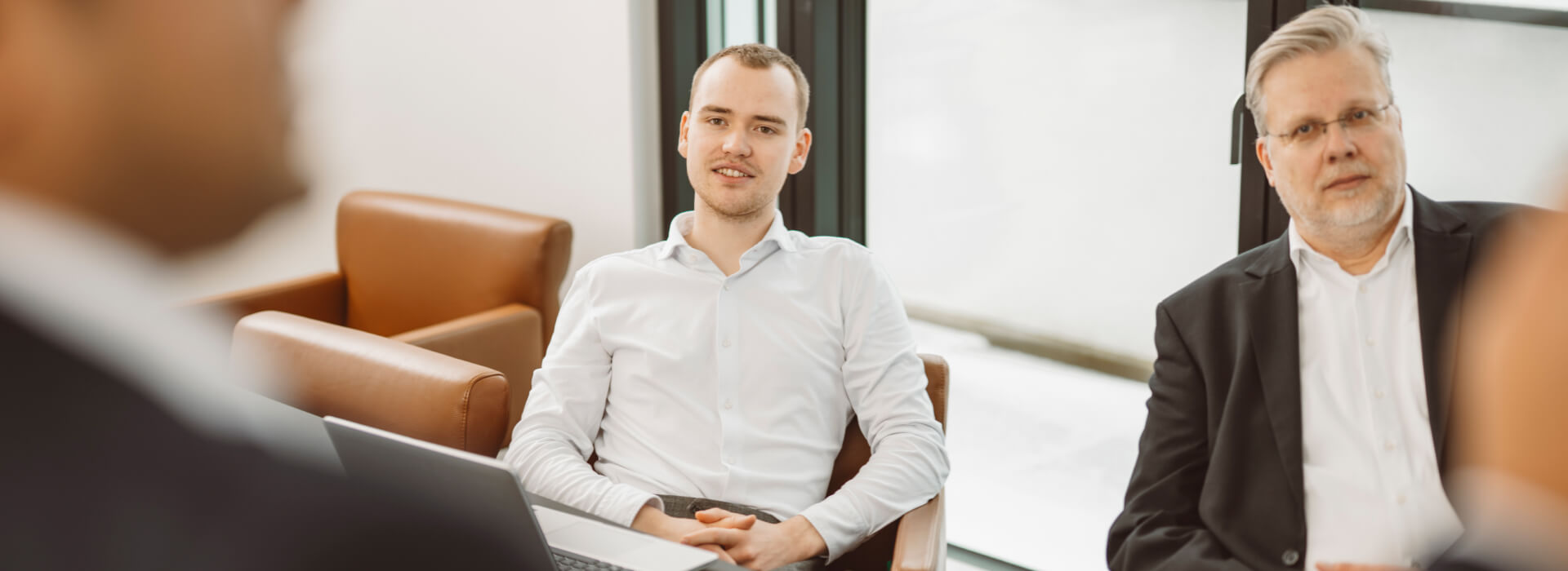 Mehrere Mitarbeiter sitzen an einem Konferenztisch und sprechen über Consulting Services, Digitalisierung und Unternehmensprozesse.