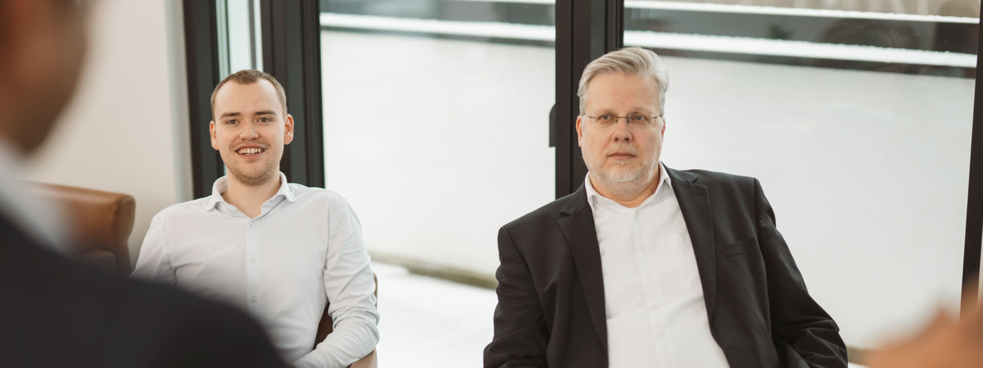 Drei Personen in einer Business-Besprechung, konzentriert auf Abstimmung und digitale Unternehmensprozesse.