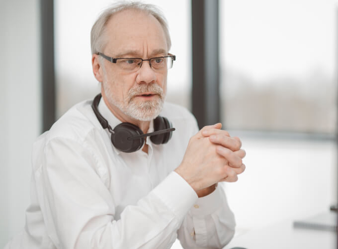 Mitarbeiter sitzt mit Headset am Arbeitsplatz und arbeitet am Bildschirm an Prozessoptimierung.