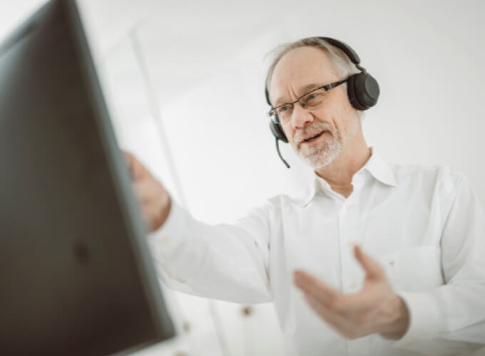 Mitarbeiter mit Headset in einer digitalen Besprechung, konzentriert auf Abstimmung und strukturierte Unternehmensprozesse.